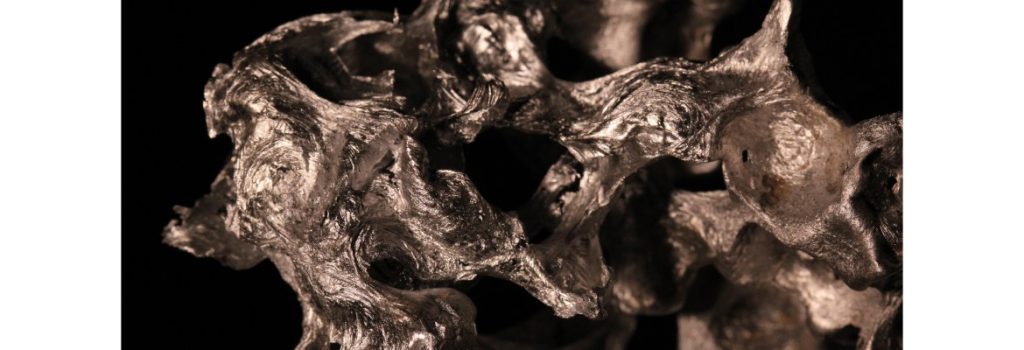 Smelted aluminium from used tonic cans poured over aqua beads to produce a silver, grey and black 3D sculpture.