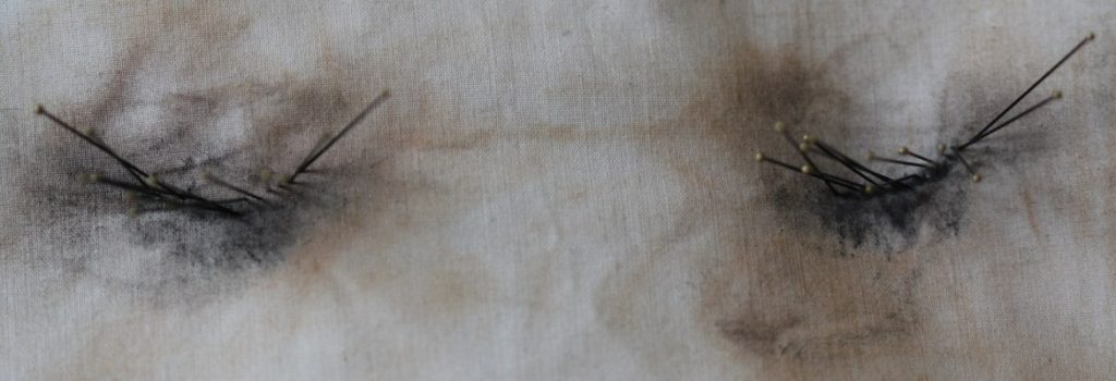 Mark-making using the sheet from my mother's bed to remove 6 months of her make-up worn daily and removed onto the sheet. Etymological pins placed where the eyelashes would be. Muted colours of foundation - peach and brown, accents of dark black where the mascara was removed onto the sheet.